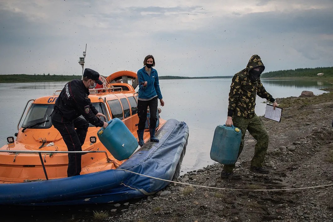 Policeman carrying fuel away from our boat. Photo: Yury Kozyrev, Novaya Gazeta