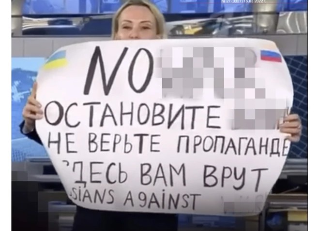 Marina Ovsyannikov holds a banner interrupting the most popular news show online in prime time on the Channel One. Screenshot and pixelized by Novaya