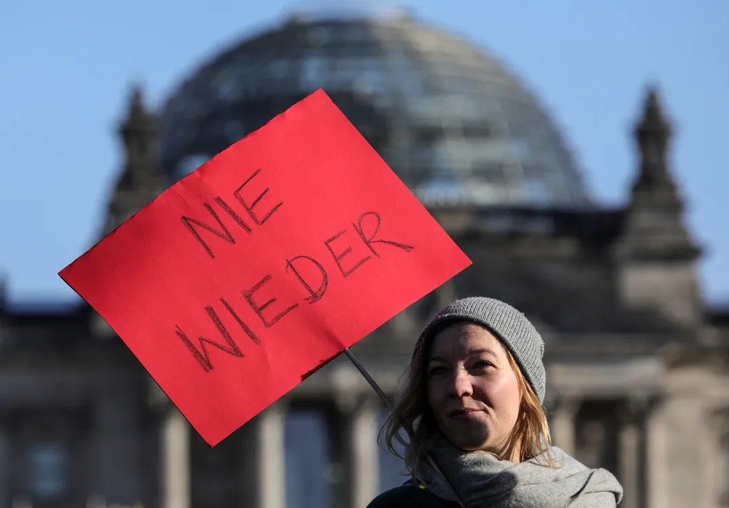 Протестующая против сотрудничества демократов с правыми возле Рейхстага, Берлин. Надпись на табличке: «Никогда больше». Фото: EPA