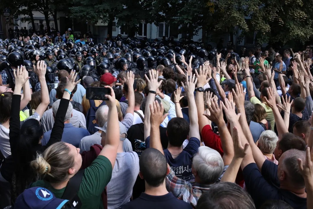 «Мы без оружия!» — кричат люди полицейским и поднимают руки вверх. Фото: Анна Артемьева / «Новая газета»