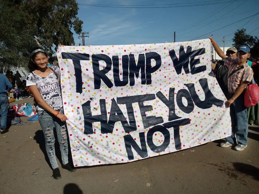 Андреа из Гватемалы и Джим из Гондураса держат простыню с надписью «Трамп, мы не ненавидим тебя». Фото: Мария Антония Эсменхау Пинеда, специально для «Новой»