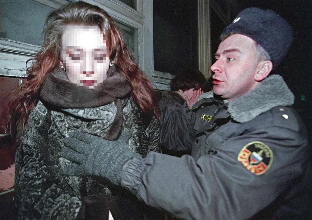 Сотрудник московской милиции заставляет женщину, подозреваемую в занятии проституцией, смотреть в камеру во время рейда. 2001 год. Фото: EPA (лицо женщины скрыто «Новой газетой»)