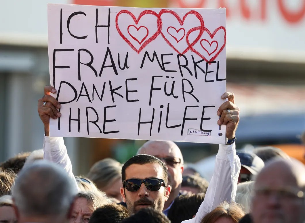 Надпись на плакате: «Я люблю фрау Меркель. Спасибо за вашу помощь!» Подпись ручкой: «Беженец». Фото: EPA