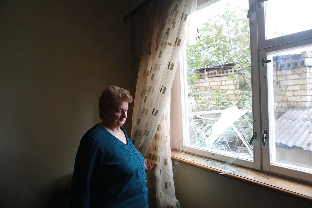Местная жительница у разбитого окна своей квартиры после бомбежки жилого сектора. Фото Павел Волков, специально для «Новой»