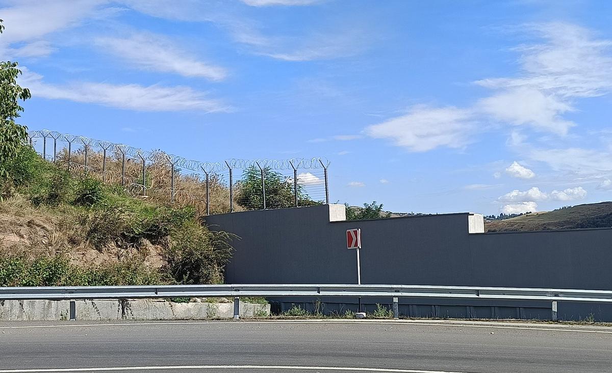 Каменная стена с колючей проволокой, закрытая железными листами, построенная в 2024 году в селе Киранц на границе Армении и Азербайджана. Фото: Андрей Мизюк