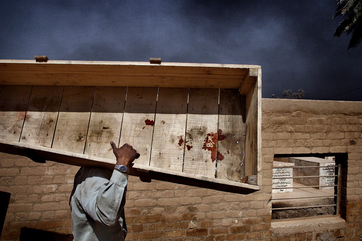 Работник кладбища несет многоразовый гроб в хранилище после похорон женщины, погибшей в результате взрыва в Багдаде. Ирак, 31 марта 2003 года. Фото: Юрий Козырев / «Новая газета»