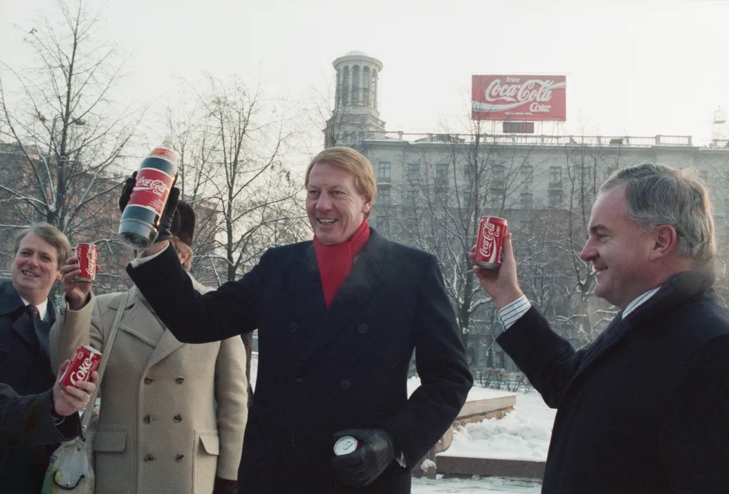 Вице президент Coca-Cola Невиль Исделл на фоне рекламного щита Coca-Cola на Пушкинской площади в Москве, 1989 г. Фото: Борис Кавашкин / Фотохроника ТАСС