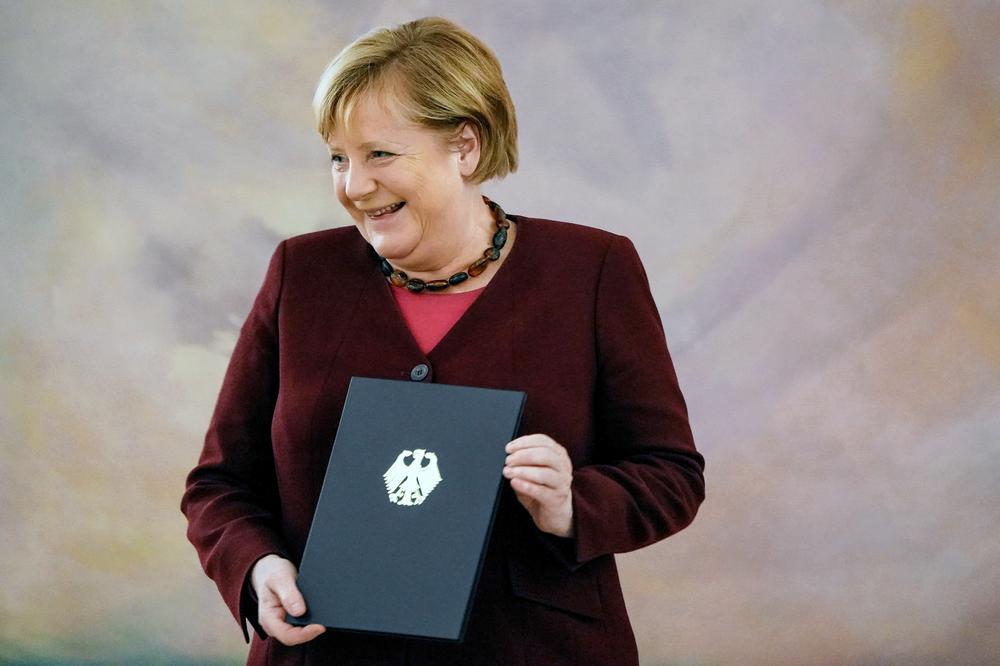 Меркель с сертификатом о прекращении полномочий. Фото: EPA