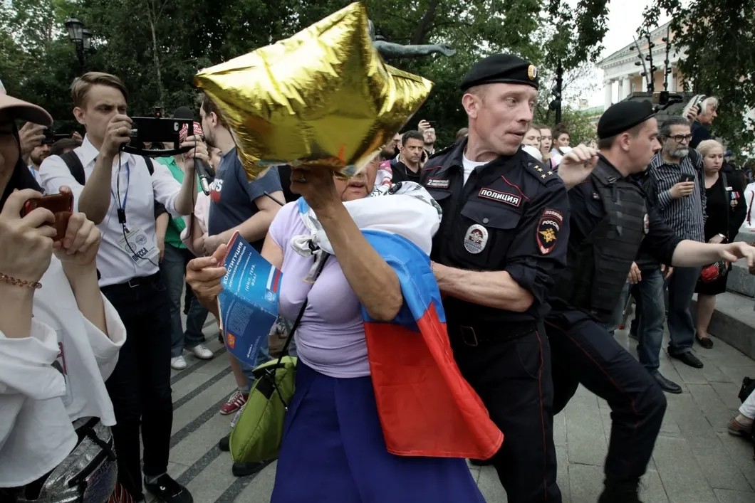 Полицейский задерживает пожилую женщину с томиком Конституции в руках. 12 июня 2019 года. Фото: Анна Артемьева / «Новая газета»