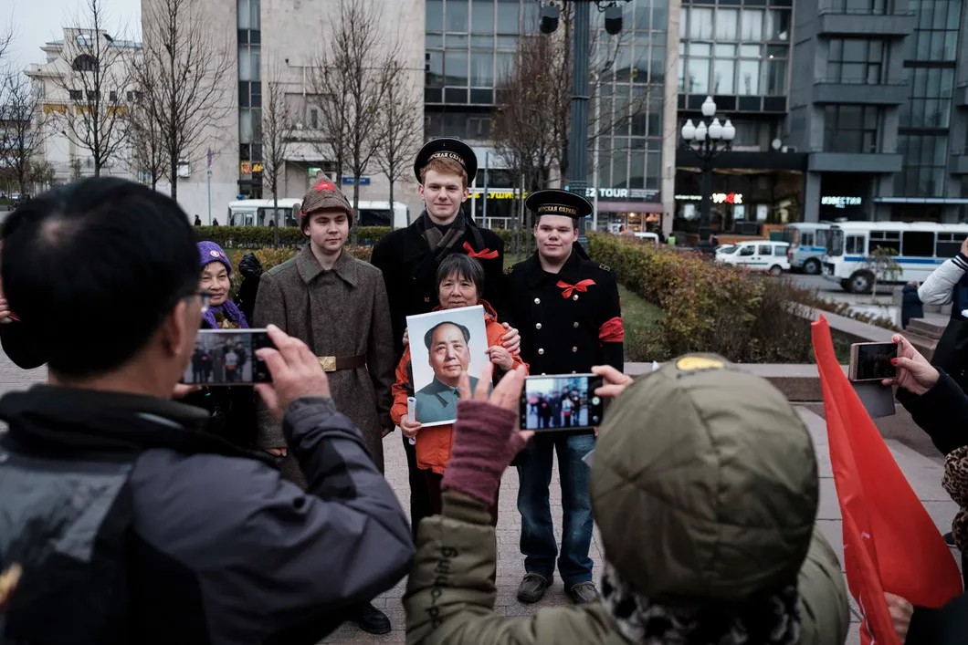 Коммунистка из Китая с портретом Мао фотографируется с российскими молодыми людьми в костюмах времен Октябрьской революции. Фото: Антон Карлинер / специально для «Новой»