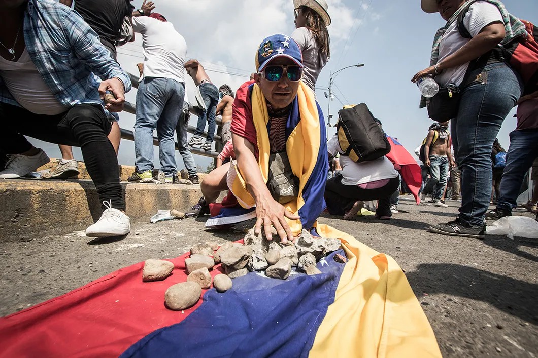 Протестующие собирают камни в венесуэльский флаг, чтобы отнести их к месту столкновений. Фото: Родольфо Чурион