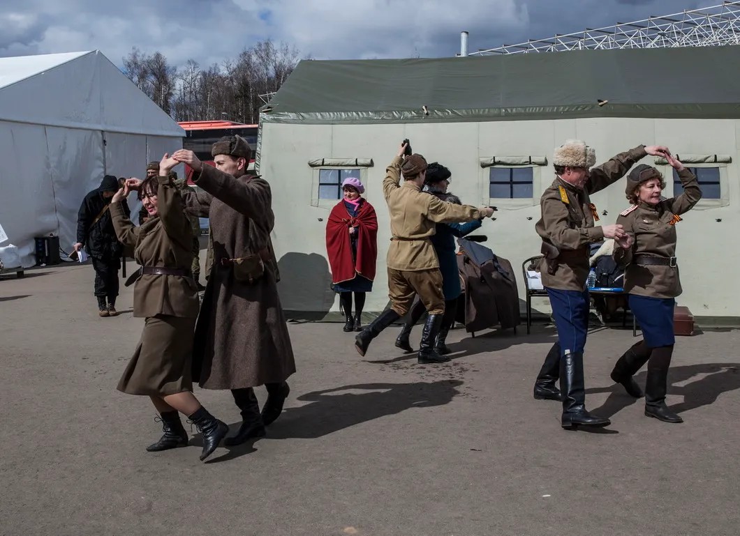 Участники реконструкции танцуют за трибунами. Фото: Влад Докшин / «Новая газета»