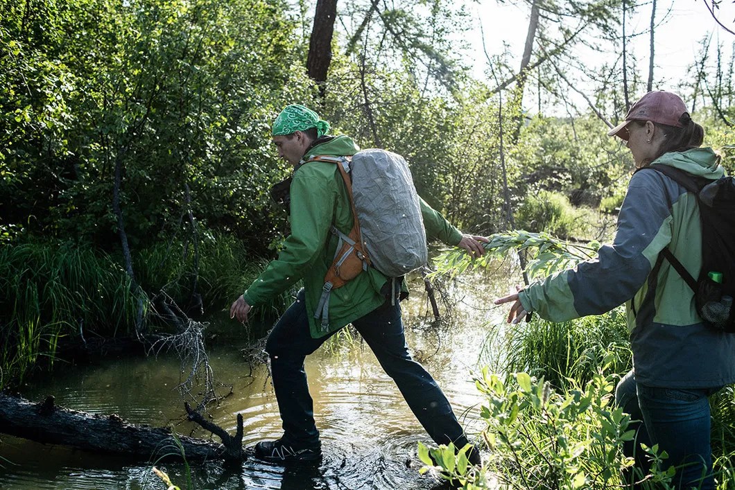 Vasiliy and Maria Ryabinina crossing a stream near the Talnakh Enrichment Factory tailings storage facility. Photo: Yury Kozyrev, Novaya Gazeta