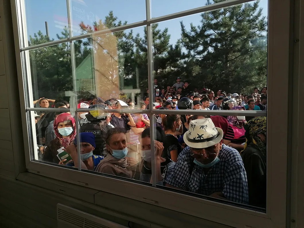 Люди заглядывают в здание вокзала через окно. Фото: Елена Романова / «Новая газета»