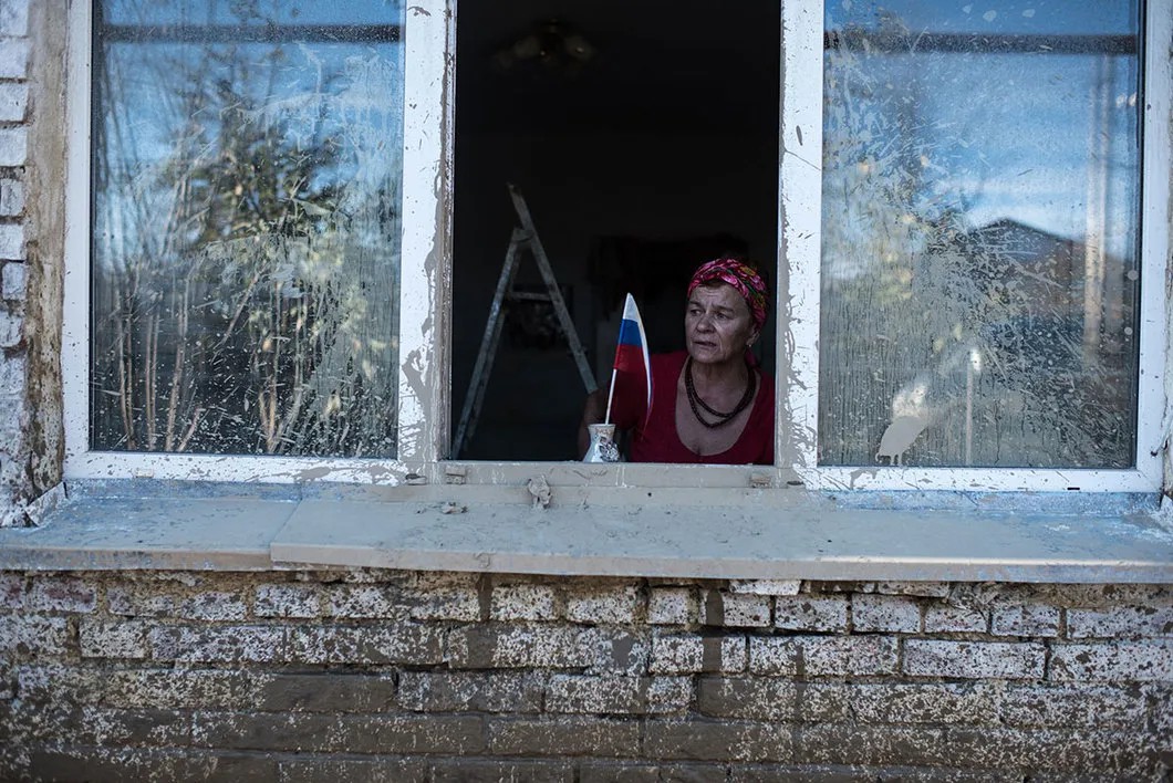 Жительница станицы Кабардинской смотрит, как волонтеры убирают ее двор. Фото: Алина Десятниченко, специально для «Новой»