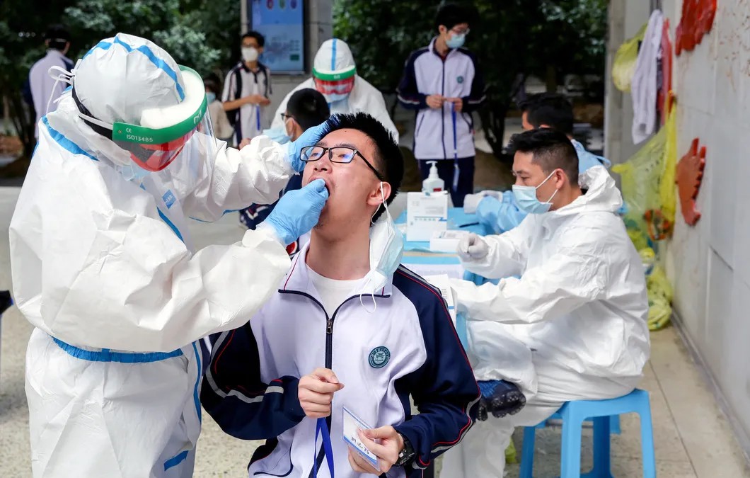 Рабочие в защитных костюмах берут мазки у старшеклассников. Фото: Reuters
