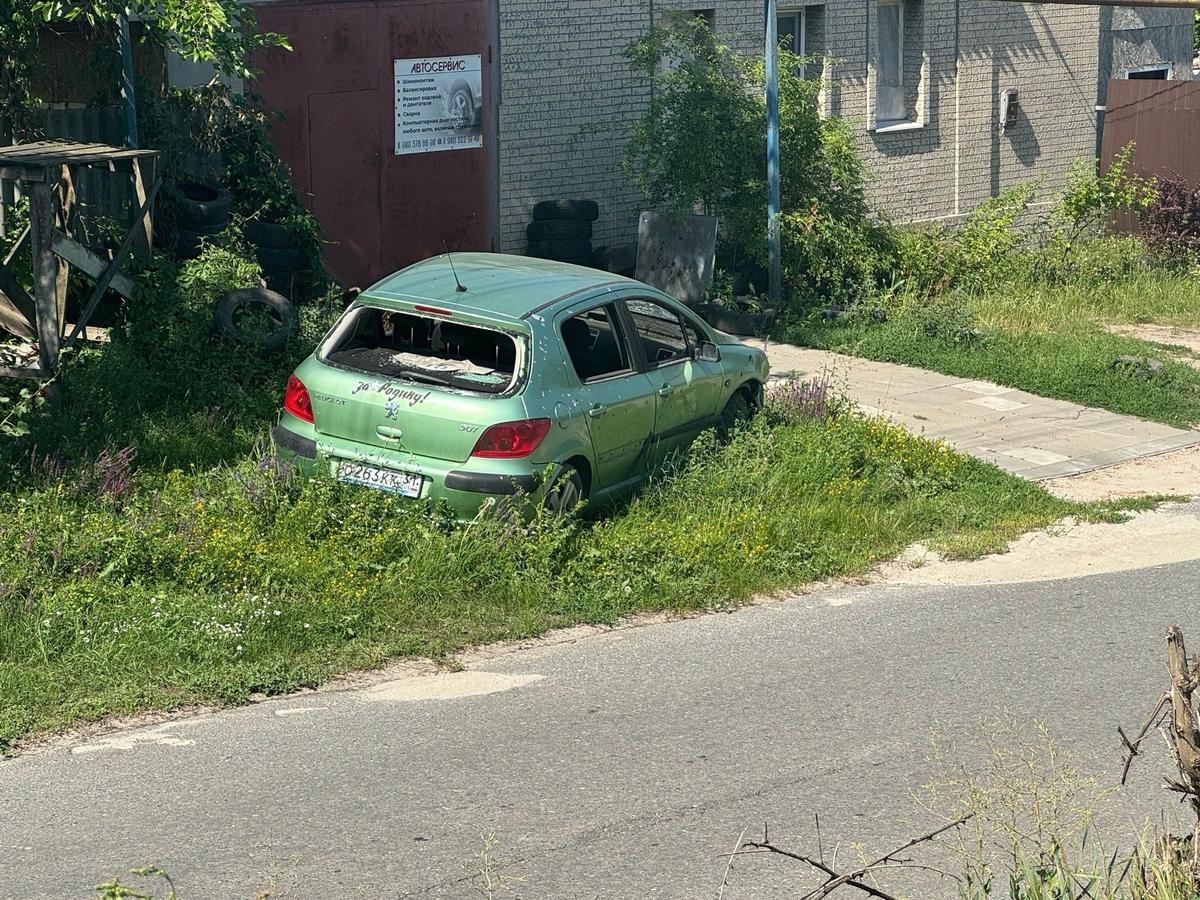 На обочине стоит зелёная Peugeot с гравировкой «За родину!» на капоте. Она изрешечена маленькими, словно пули, осколками. Фото: Валерия Кайдалова / Fonar.tv