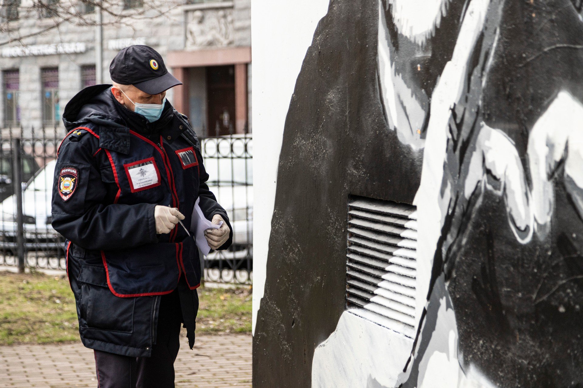 Полицейский соскребает с рисунка образцы краски. Фото: Иван Петров