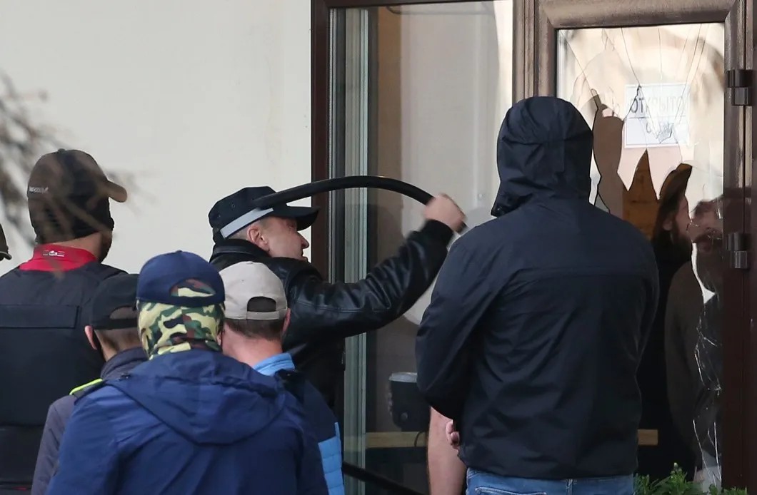 Сотрудник правоохранительных органов Николай Карпенков разбивает дверь кафе O’Petit во время акции «Марш единства» в Минске. Фото: Наталия Федосенко / ТАСС