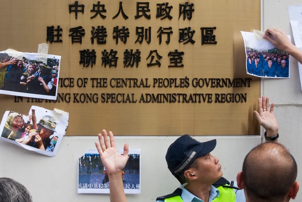 Протестующие в Гонконге прикрепляют фотографии заключенных уйгуров-мусульман в Синьцзяне. Фото: EPA