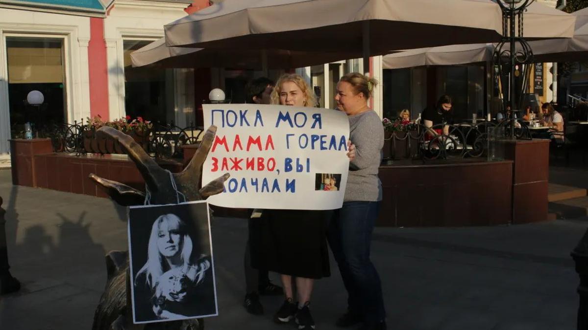Дочь погибшей Ирины Славиной возле ее портрета с плакатом. Фото: Светлана Виданова / «Новая газета»