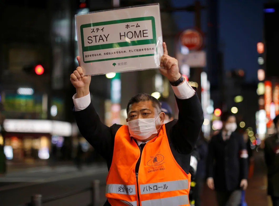 Муниципальный служащий в Токио с табличкой-напоминанием: «Оставайтесь дома». Фото: Reuters