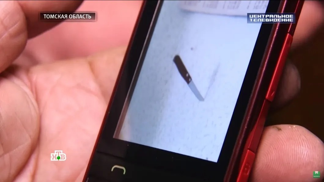 Александр Жуков показвывает сфотографированный нож — доказательство «Полтергейста». Скриншот выпуска программы «Центральное телевидение»