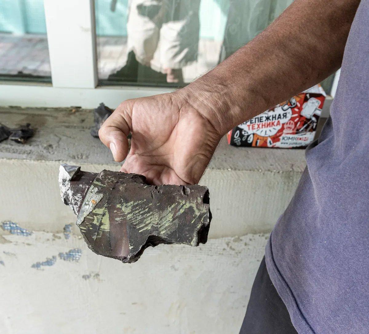 Александр показывает осколки снарядов — тяжелые, весом больше килограмма. Фото: Арден Аркман / «Новая газета»