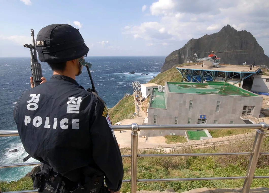 Южнокорейский полицейский охраняет границу, вдали виден один из двух островов Токто (группа островов Лианкур, российское название), право собственности на которые оспаривают Корея и Япония. Фото: Reuters