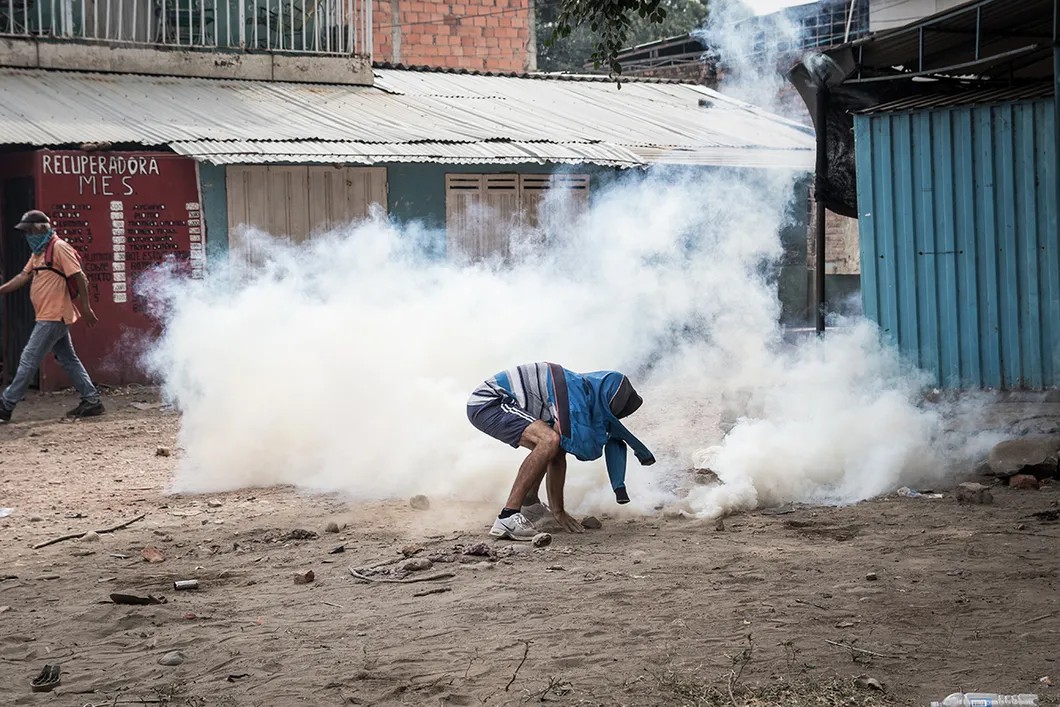 Подростки тушат газовые гранаты, сброшенные с моста Симона Боливара. Гранаты закидывают песком. Кукута, Колумбия. Фото: Родольфо Чурион