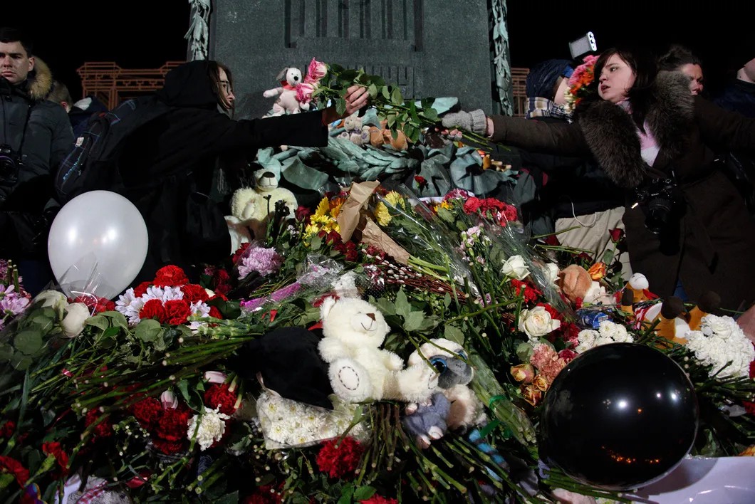 Люди передают цветы и свечи через головы друг друга к памятнику. Фото: Виктория Одиссонова / «Новая газета»