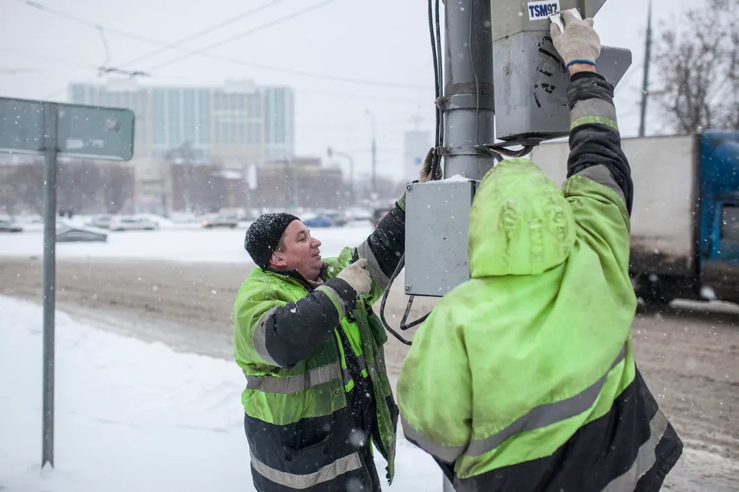Дмитрий и Валерий счищают со светофора «вандальные» наклейки. Фото: Влад Докшин / «Новая»