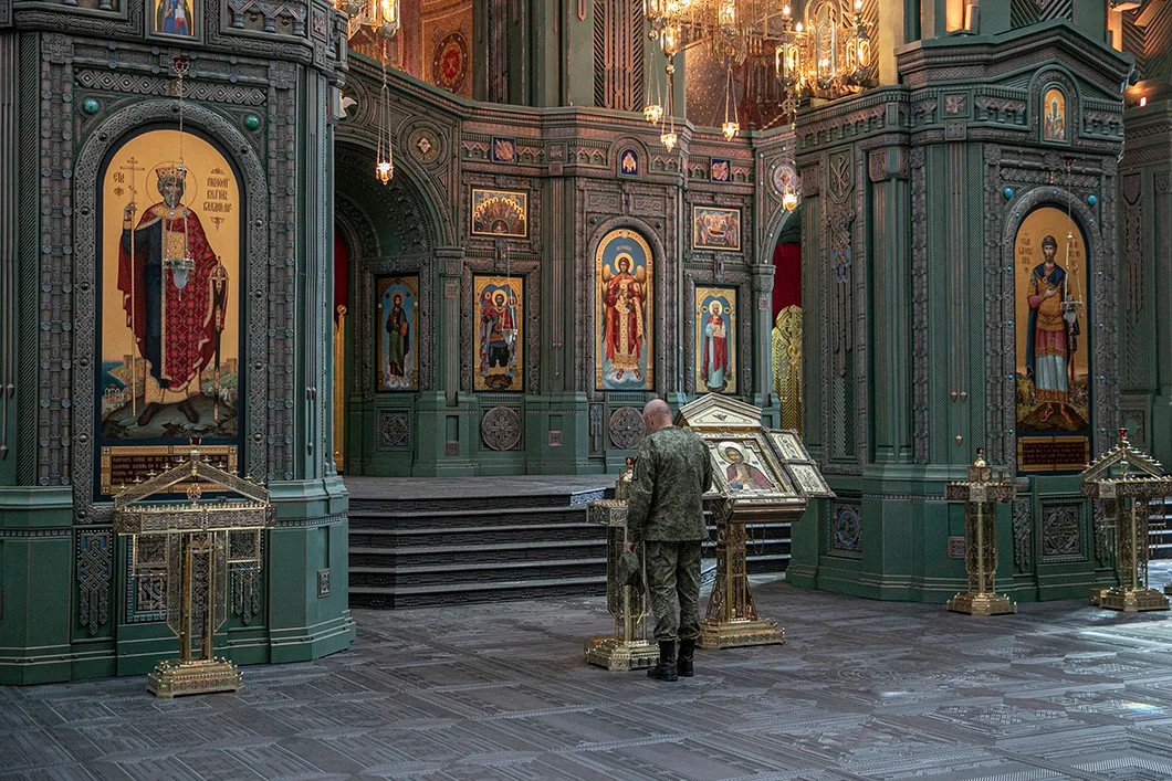 Военнослужащий ставит свечу. Фото: Влад Докшин / «Новая газета»
