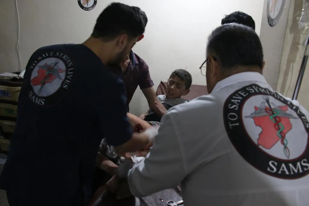 Медики в форме «Сирийского американского медицинского общества» осматривают раненого. Фото к материалу предоставлены активистами «Сирийского американского медицинского общества», а также медиаактивистом, жителем Идлиба Абдурахманом А.
