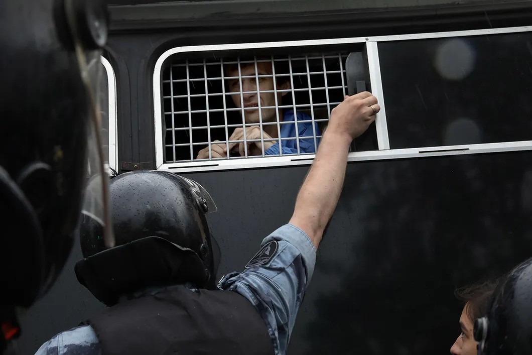 Полицейский захлопывает окно автозака. Фото: Анна Артемьева / «Новая газета»