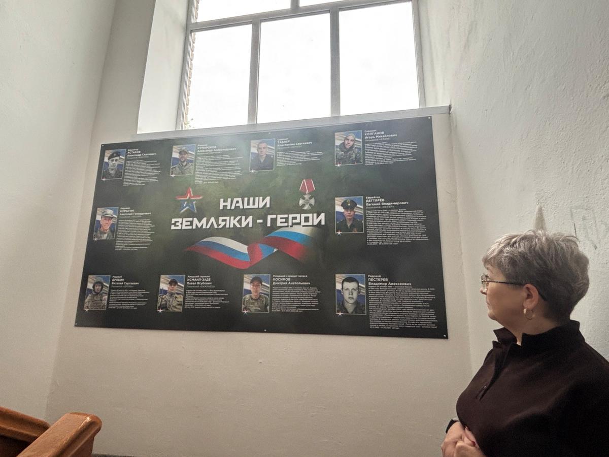 Учитель берлинской школы перед плакатом с погибшими селянами. Фото автора