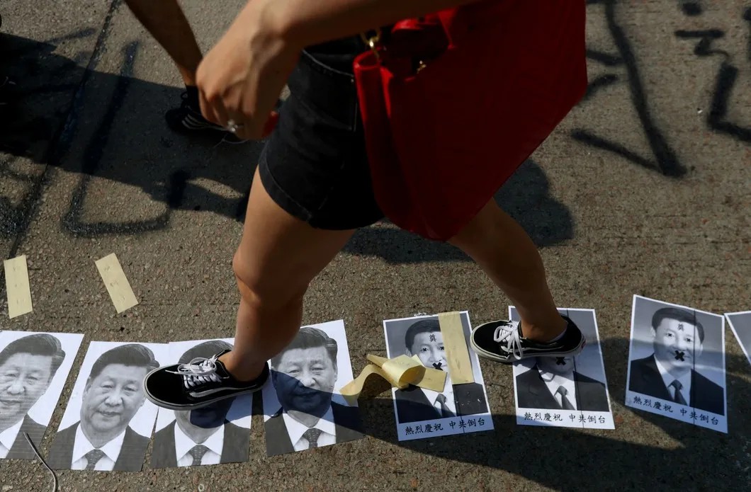 Гонконгские протестующие наступают на фотографии президента Китая Си Цзиньпина. Фото: Reuters
