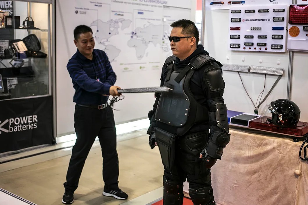 Сотрудники китайской фирмы «Веньжоу» демонстрируют прочность своей спецодежды для полицейских. Фото: Влад Докшин / «Новая газета»