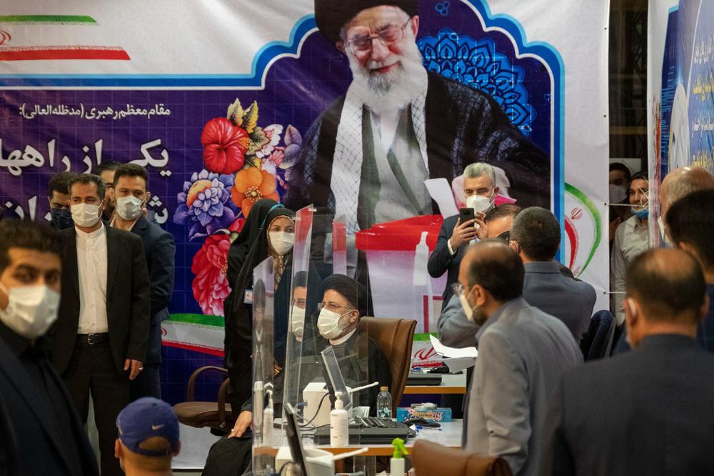 Эбрахим Раиси (в центре) сидит под портретом верховного лидера Ирана аятоллы Али Хаменеи во время регистрации в качестве кандидата на выборах президента Ирана, 15 мая 2021 года. Фото: Morteza Nikoubazl / NurPhoto / Getty Images