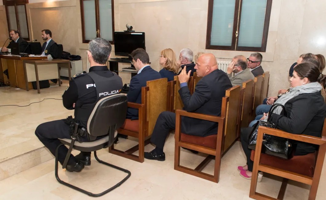 Адвокат Александр Романов (на первом ряду рядом с полицейским) и другие на заседании суда по делу об отмывании 14 миллионов евро представителями «русской мафии» в Испании. Фото: EPA