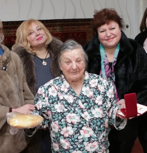 Майя Хужина (на заднем плане слева) поздравила блокадницу медалью и хлебом. Фото: сайт Керченского горсовета (сейчас — уже удалено)
