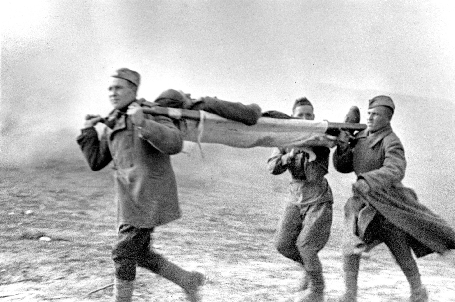 Солдаты выносят раненого с поля боя. Фото: Леонид Доренский / ТАСС