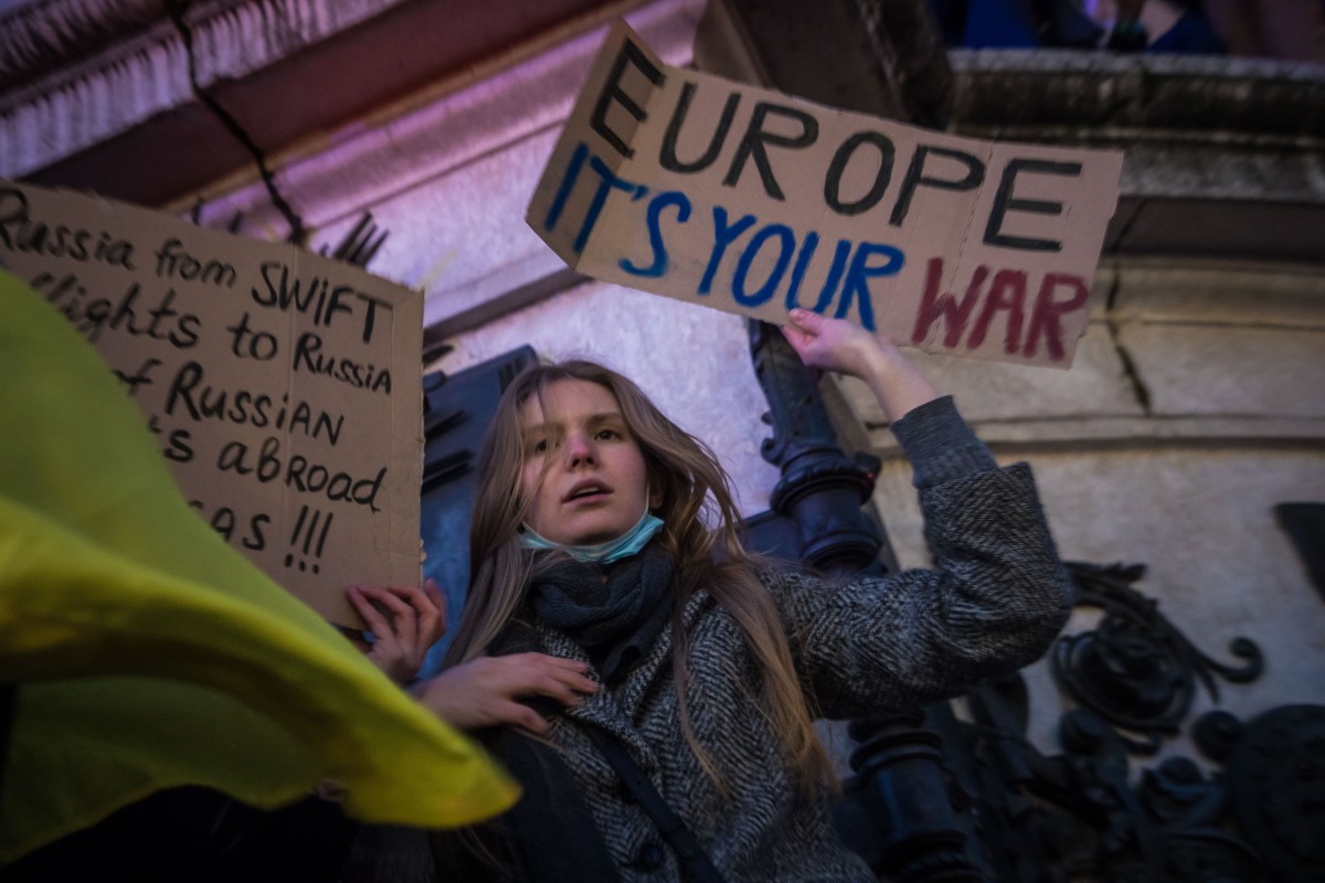 «Европа, это твоя война!» — надпись на плакате. На другом протестующий требует отключения России от SWIFT. Митинг против российской агрессии в Украине, Париж, 24 февраля, 2022. Фото: EPA