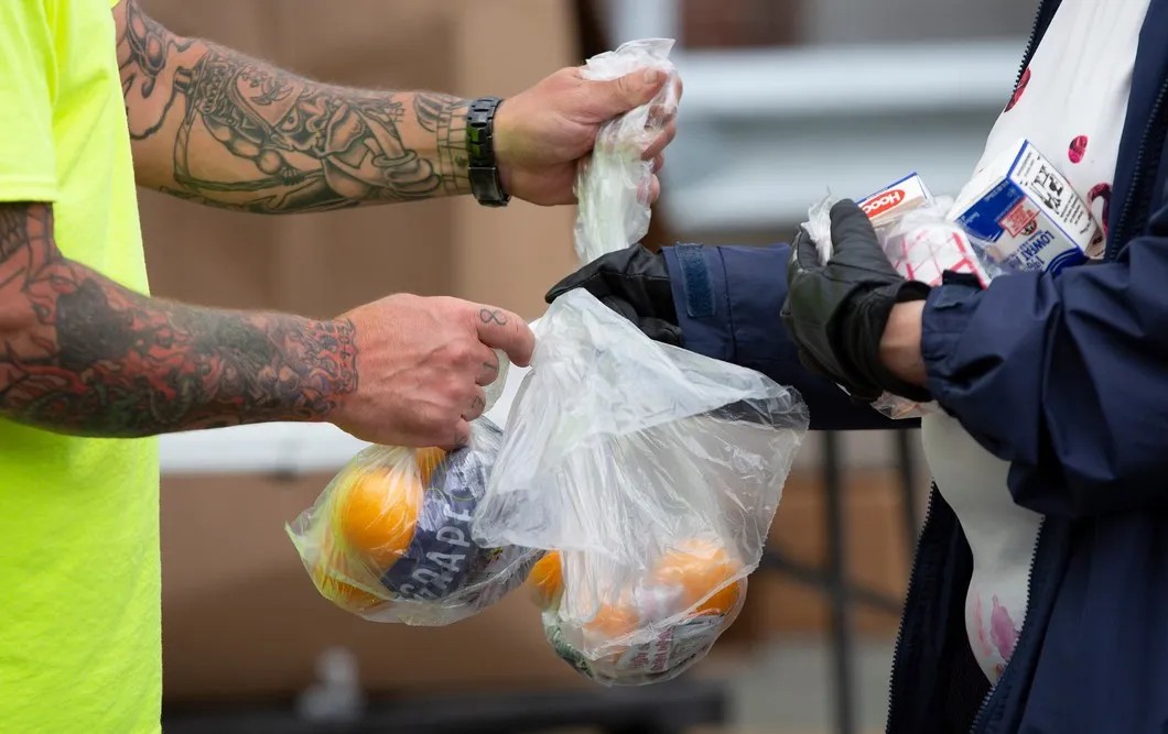 Городской служащий передает местному жителю пакеты с фруктами. Штат Массачусетс, США. Фото: ЕРА