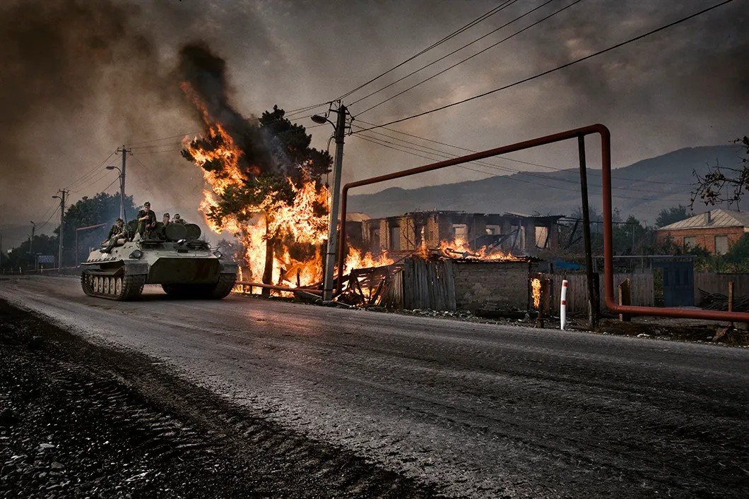 Российский БТР возле дома, подожженного ополченцами из Южной Осетии, в грузинской деревне Квемоачебети, Цхинвал. 2008 год. Фото: Юрий Козырев