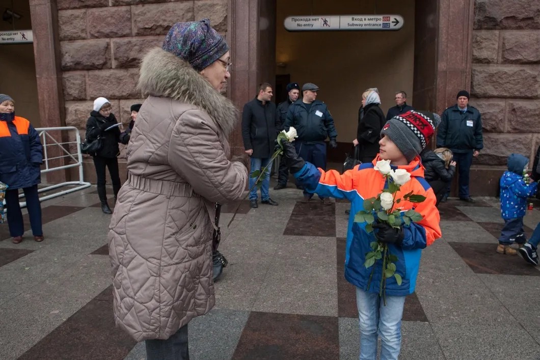 Максим, сын Евгении, раздает цветы прохожим. Фото: Елена Лукьянова / «Новая газета в Петербурге»
