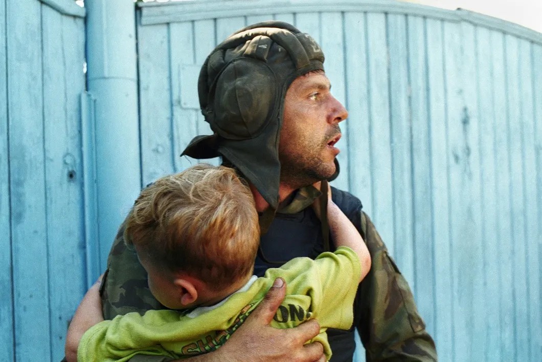 Солдат федеральных сил держит на руках ребенка, бывшего в заложниках чеченских террористов. Фото: Николай Малышев / ТАСС