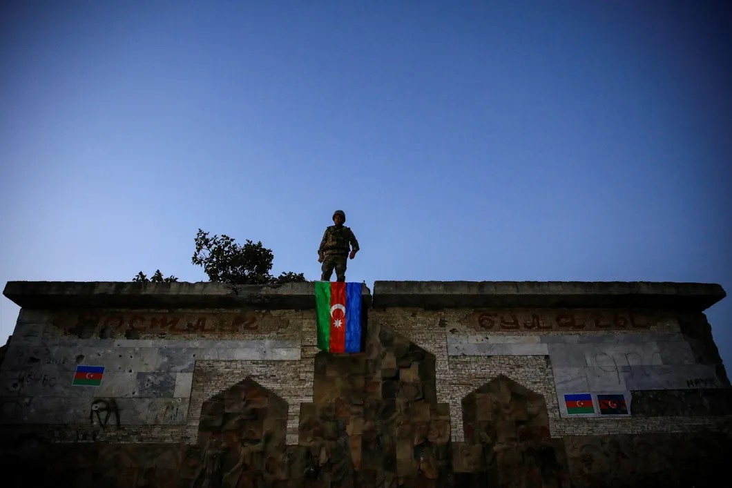 Военнослужащий вывесил флаг Азербайджана на территории Нагорного Карабаха. Фото: Reuters