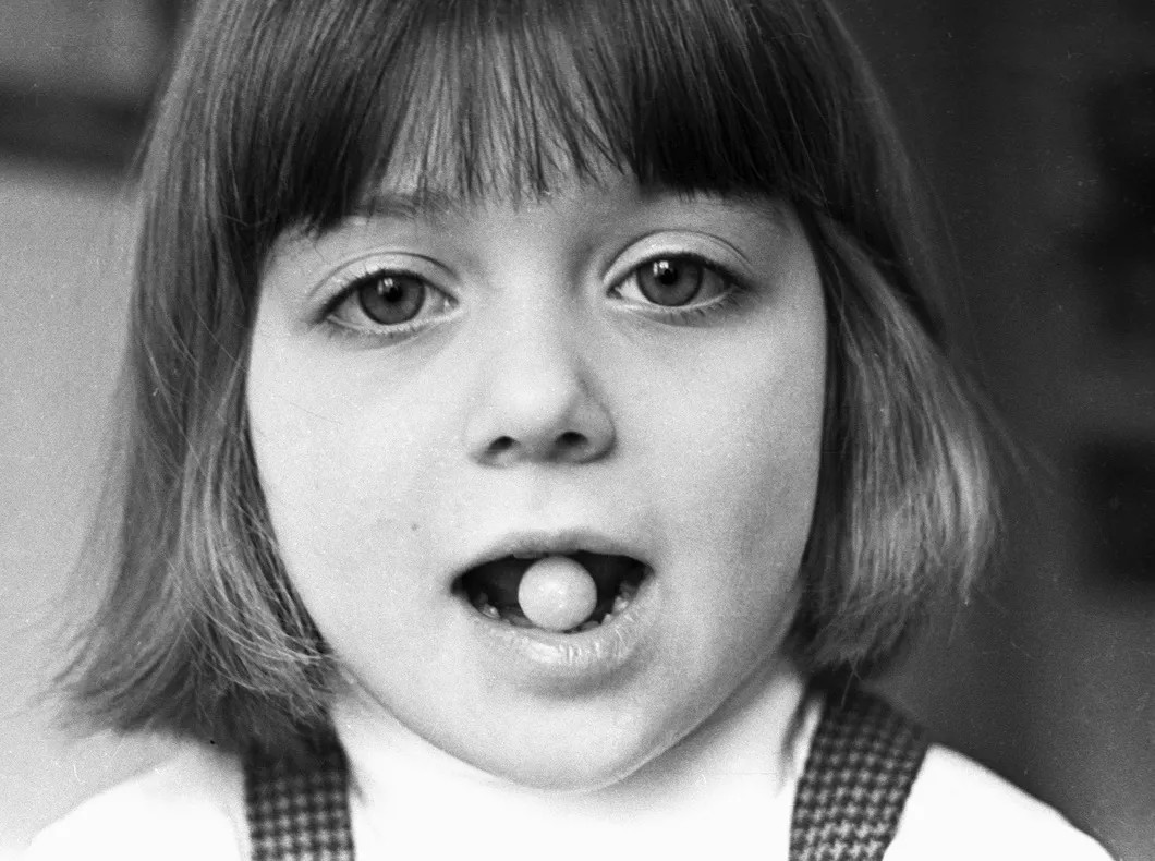 Девочка держит в зубах капсулу с вакциной в Институте полиомиелита, 1970-е гг. Фото: РИА Новости