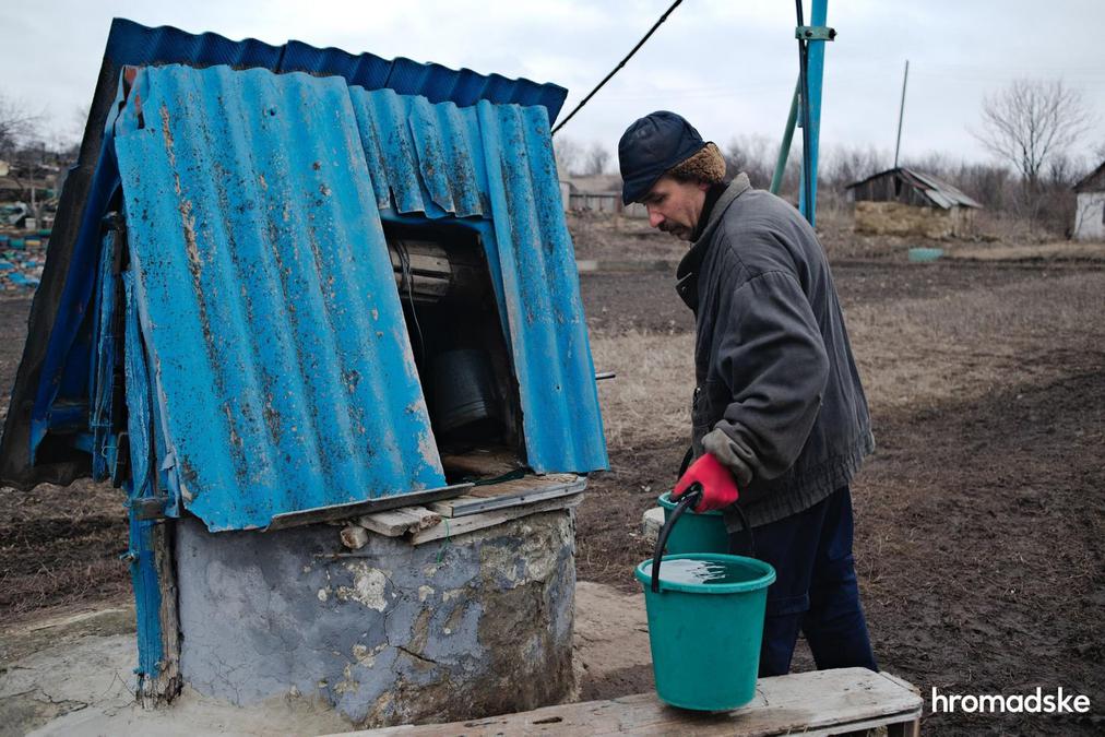 Николай Николаевич набирает воду из колодца возле своего дома в Новоалександровке. Фото: Макс Левин / hromadske
